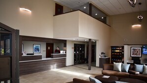 A spacious lobby with a reception desk, seating area, and a staircase leading to an upper level. - Candlewood Suites Grand Rapids Airport by IHG (Grand Rapids)