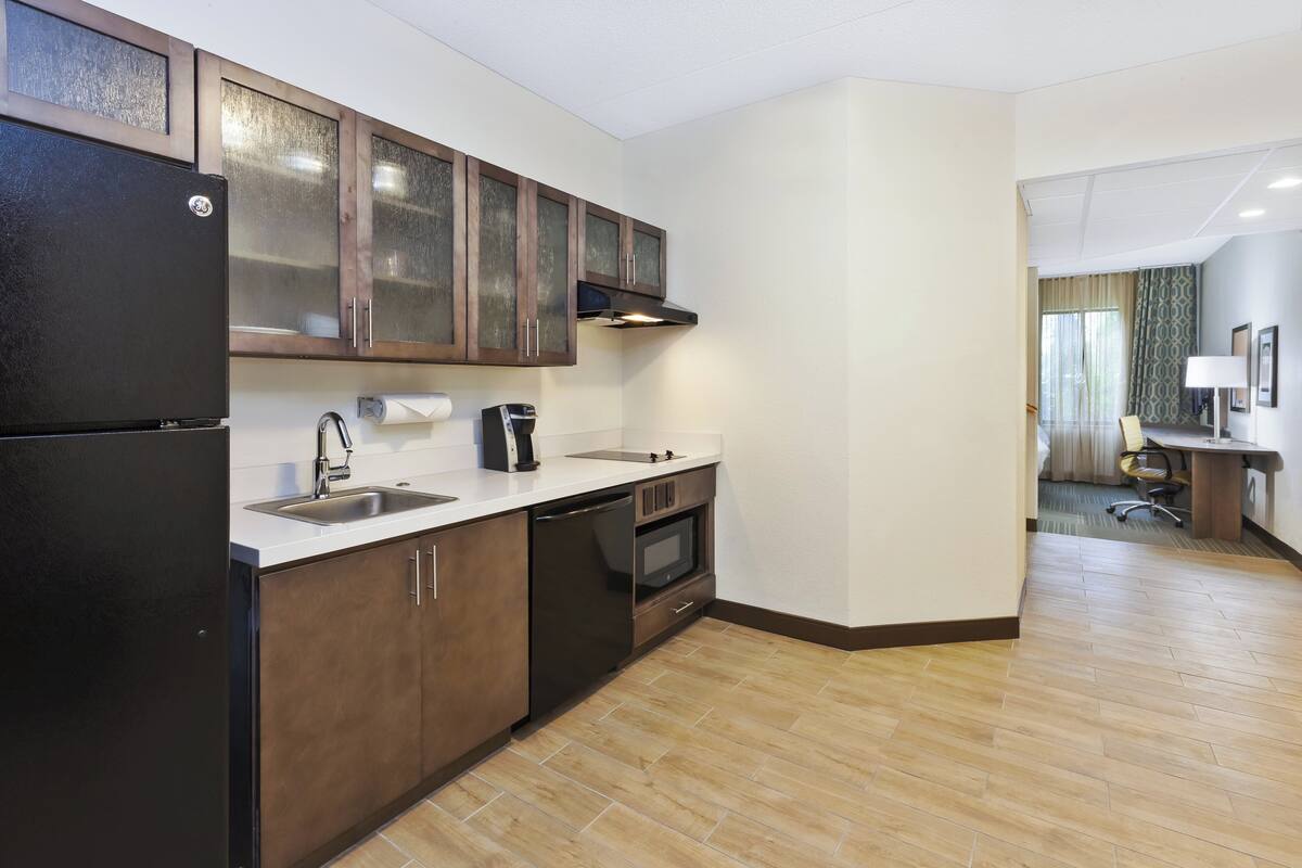 A modern kitchen with a refrigerator, stove, sink, and cabinets.