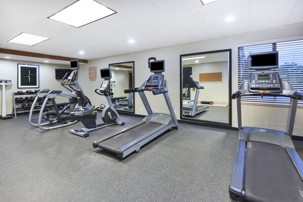 Un gimnasio con cintas de correr, elípticas y equipos de levantamiento de pesas.