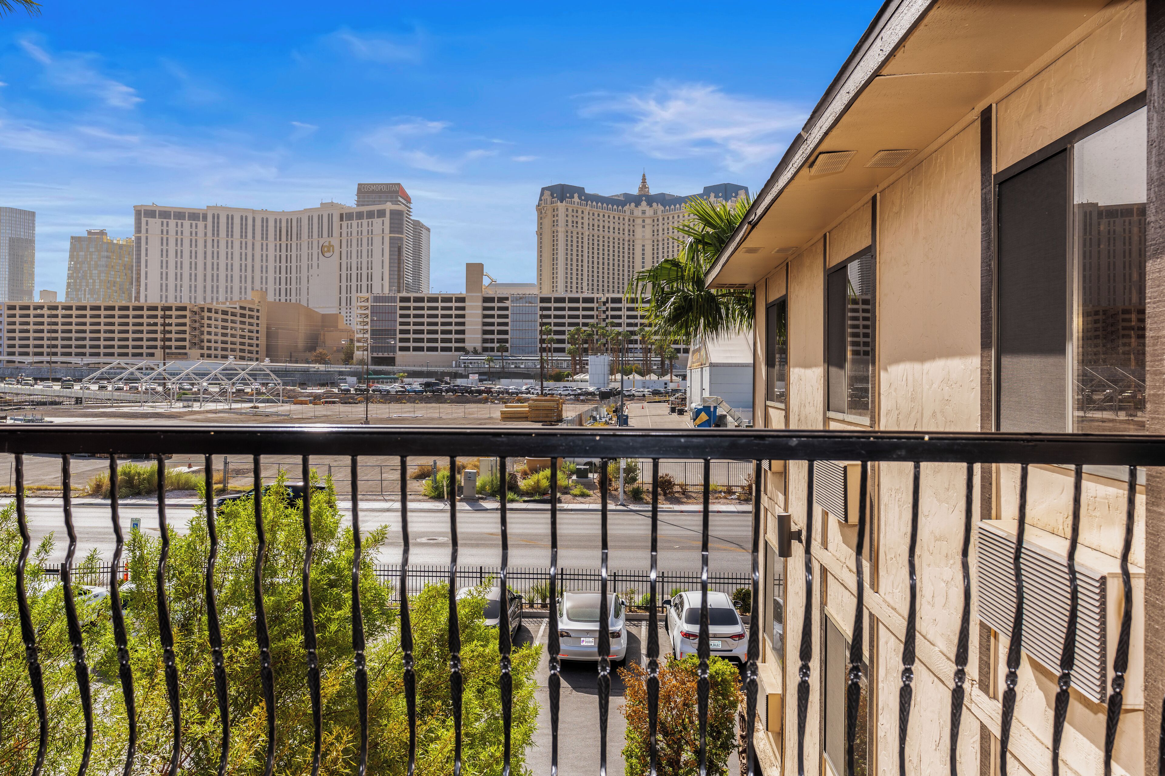A balcony with a view of a cityscape, including tall buildings and a parking lot.