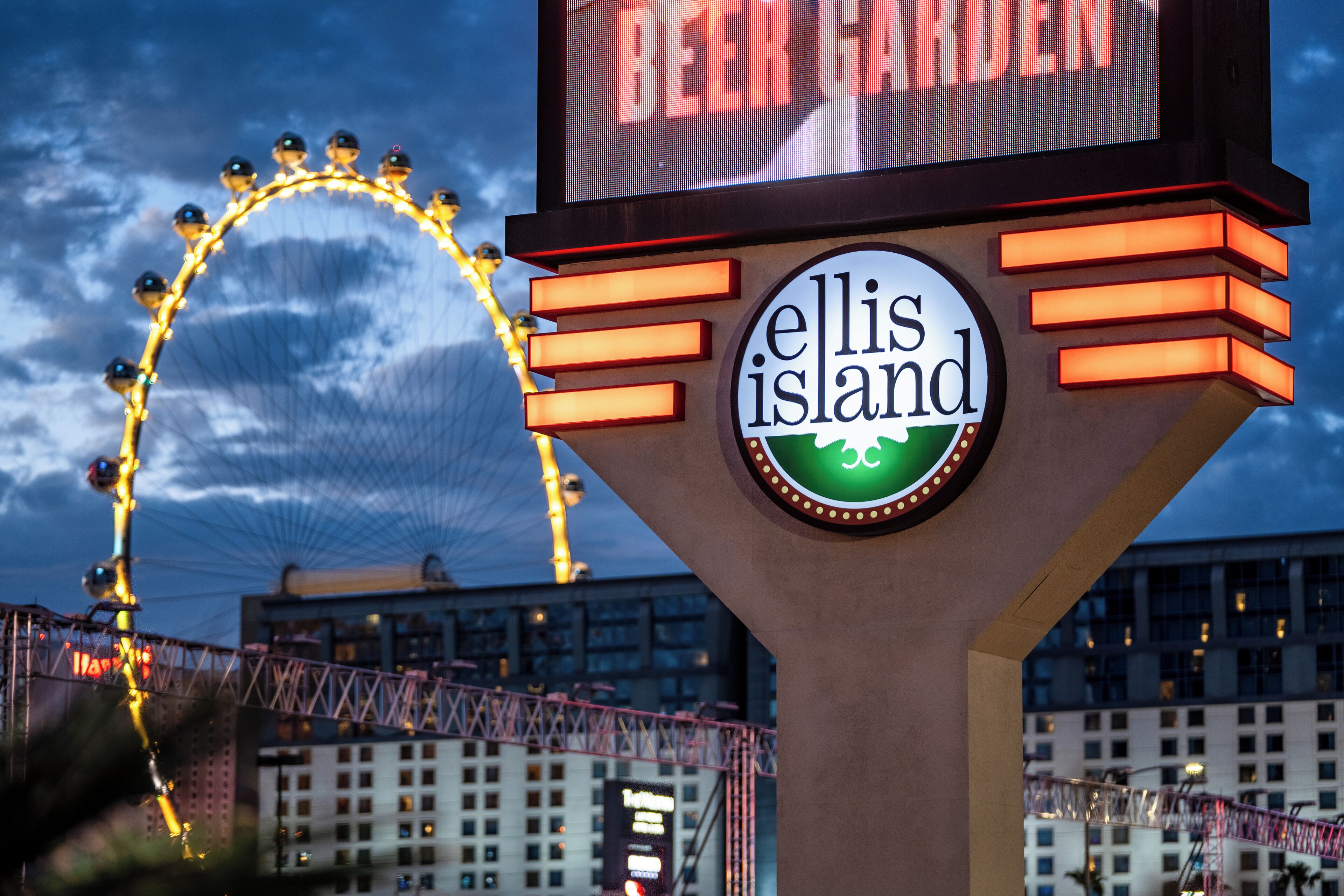 Letrero que dice 'Ellis Island', con una noria al fondo.