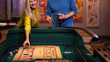 Una mesa de dados en un casino, con una mujer inclinada sobre ella y un hombre de pie a su lado.