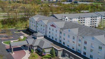 A hotel with a modern design, featuring a central courtyard with outdoor seating and a flagpole.