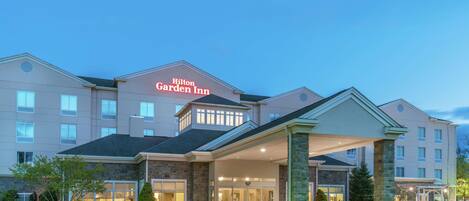 A Hilton Garden Inn hotel with a modern design, featuring a covered entrance and a landscaped front area.