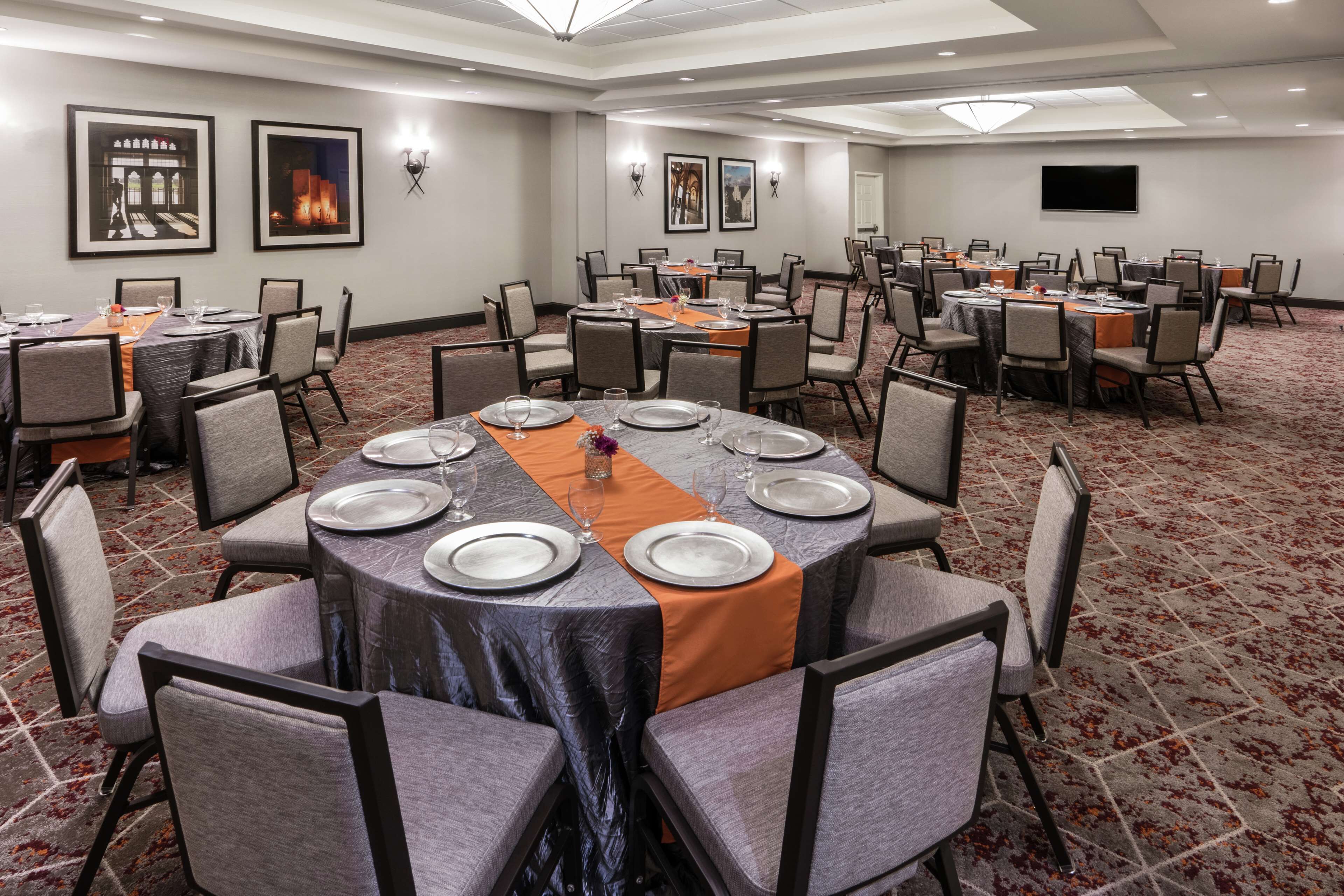 A conference room with round tables, chairs, and a carpeted floor.