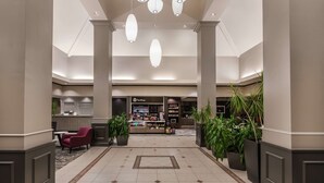 Un hall amplio con una zona de estar central, un mostrador de recepción y diversas plantas.