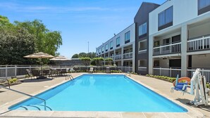 A rectangular pool with a no diving sign, surrounded by outdoor seating and a multi-story building with balconies. - Quality Inn Duluth - Atlanta Northeast (Duluth)