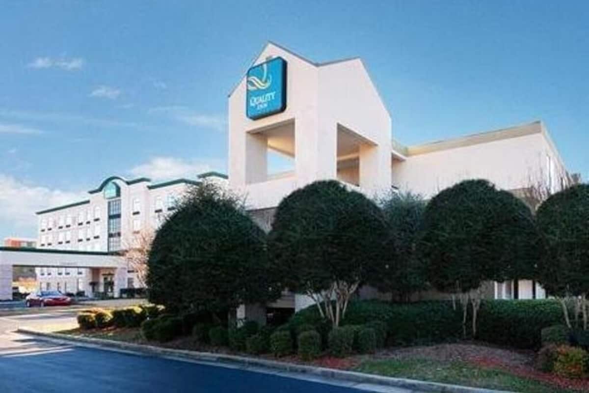 Um hotel com uma placa chamativa, estacionamento e paisagismo bem cuidado.