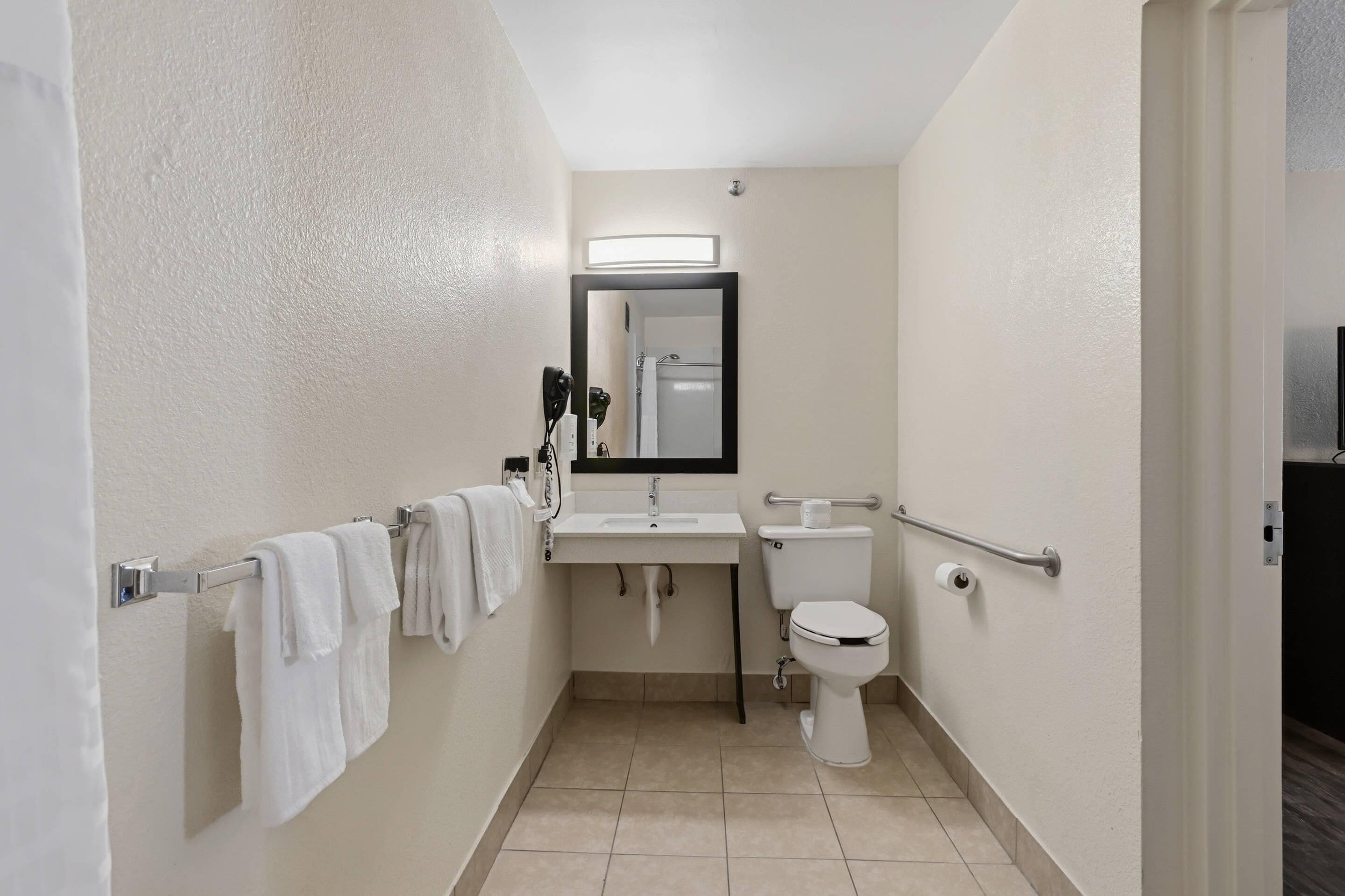Une petite salle de bain propre, équipée de toilettes, d’un lavabo et d’un miroir.