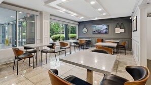 A modern dining area with glass walls, multiple tables, and chairs. - Quality Inn Duluth - Atlanta Northeast (Duluth)