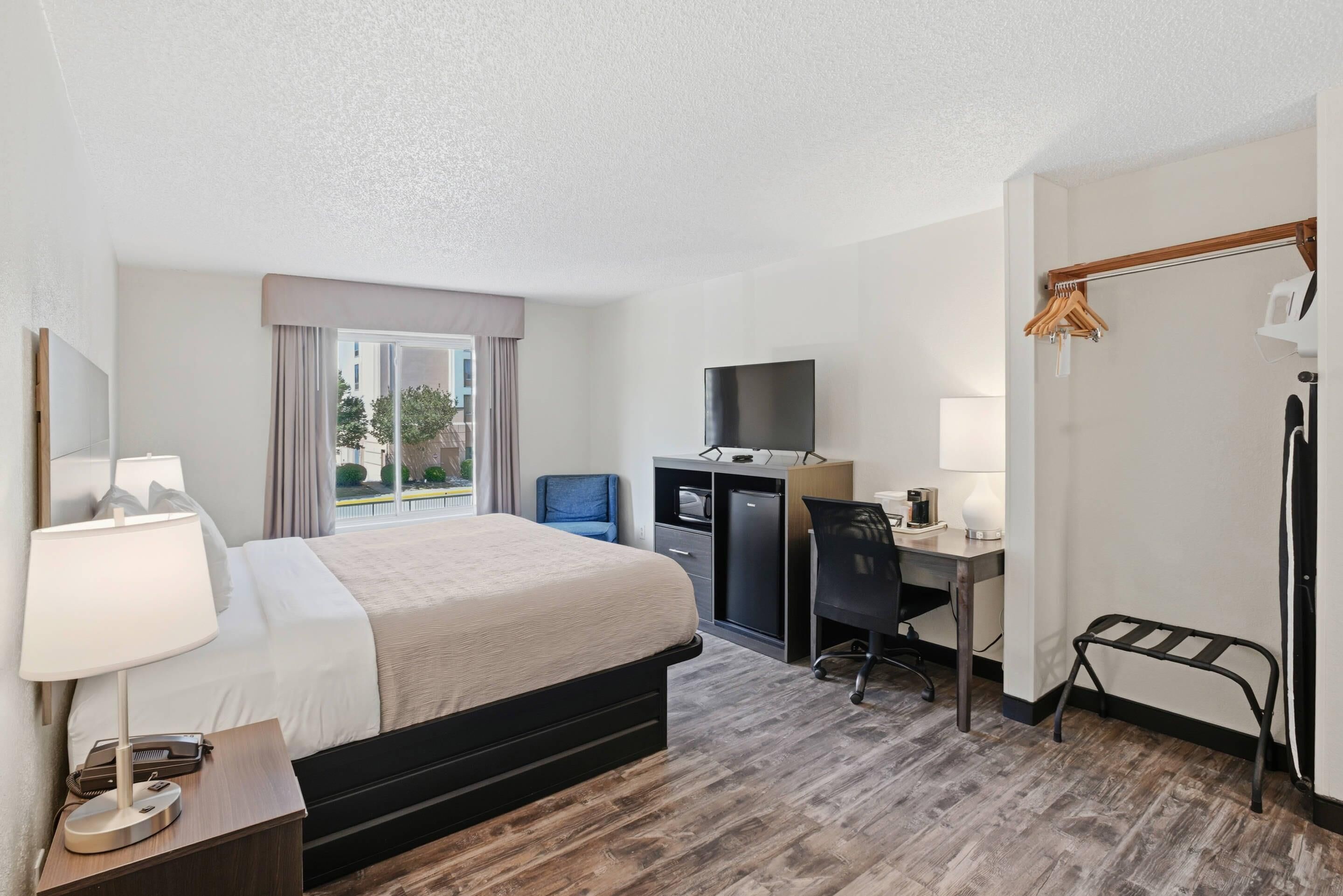 Une chambre d’hôtel équipée d’un lit, d’un bureau, d’une chaise, d’une télévision et d’une armoire.