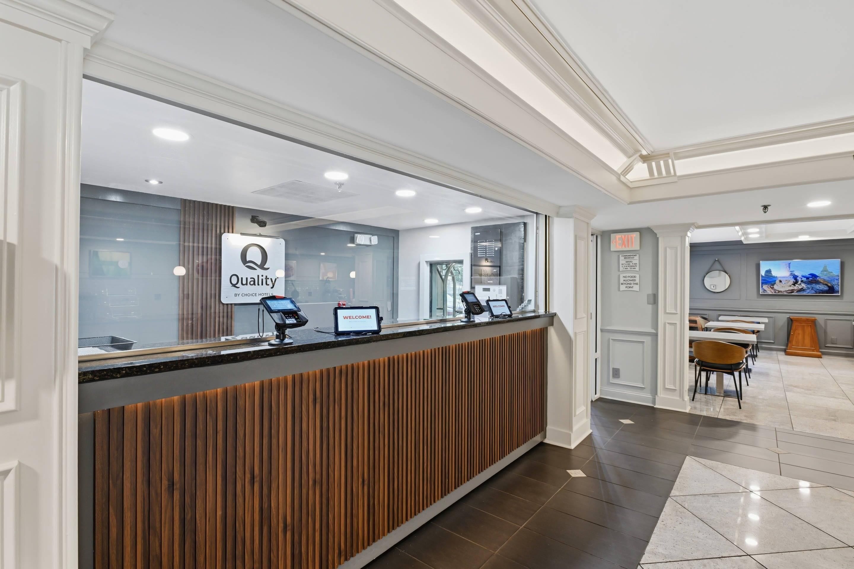 A reception desk with a 'Quality by Choice' sign, a 'Welcome' screen, and a 'Q' logo.