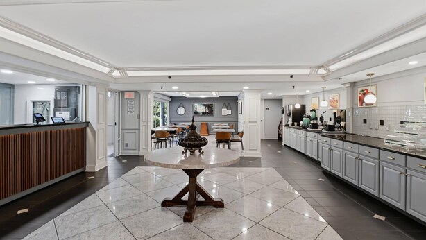 A spacious hotel lobby with a reception desk, a round dining table, and a kitchen area with cabinets and appliances. - Quality Inn Duluth - Atlanta Northeast (Duluth)