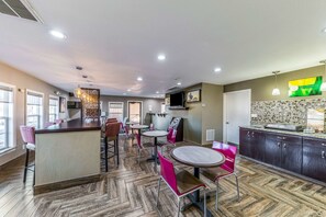 A modern restaurant with a central island, multiple seating options, and a kitchen area with a decorative backsplash.