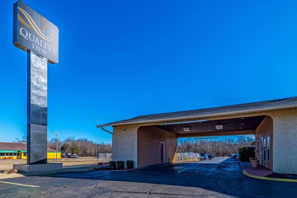 A Quality Inn with a large sign, a covered parking area, and a building with a flat roof.