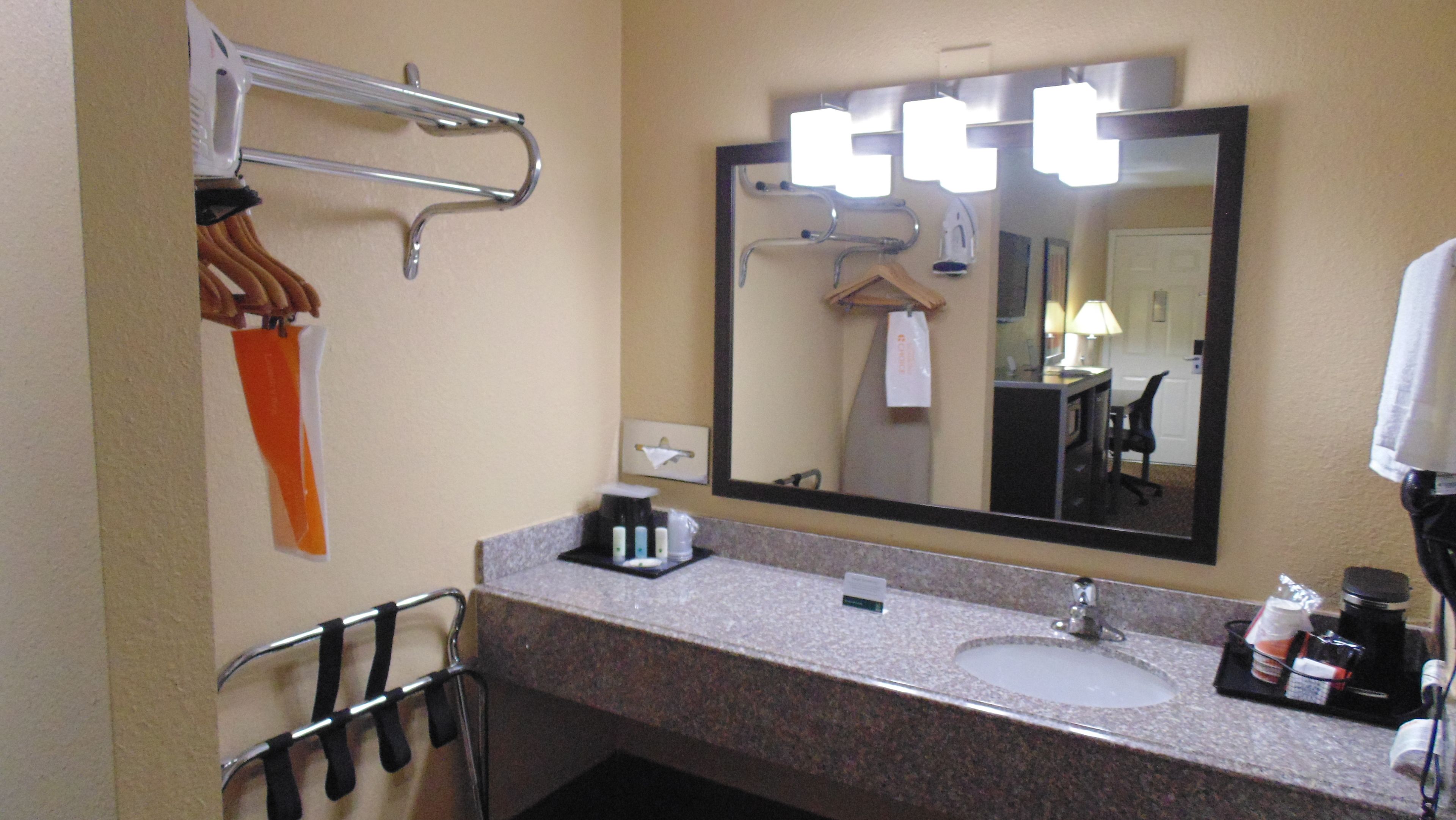 A bathroom with a sink, mirror, towel rack, and a coffee maker.