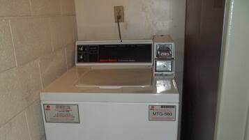 A commercial washer with a control panel, a service label, and a price tag.