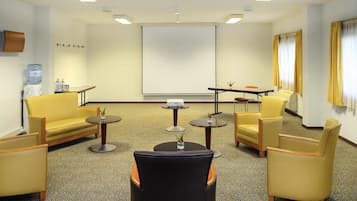 A conference room with a projector screen, a water dispenser, and seating arrangements.