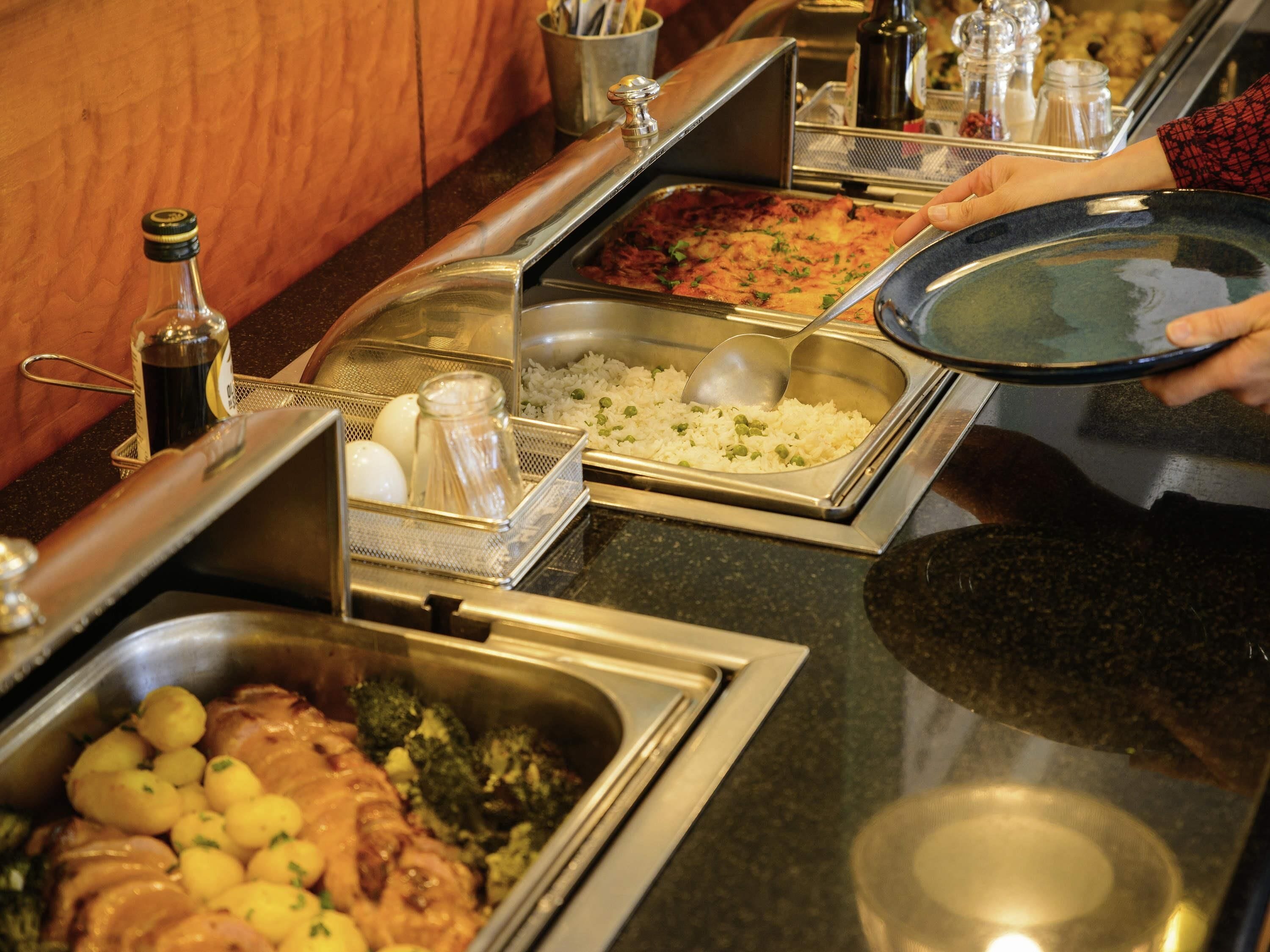 A buffet with various food options including rice, vegetables, and meat dishes.