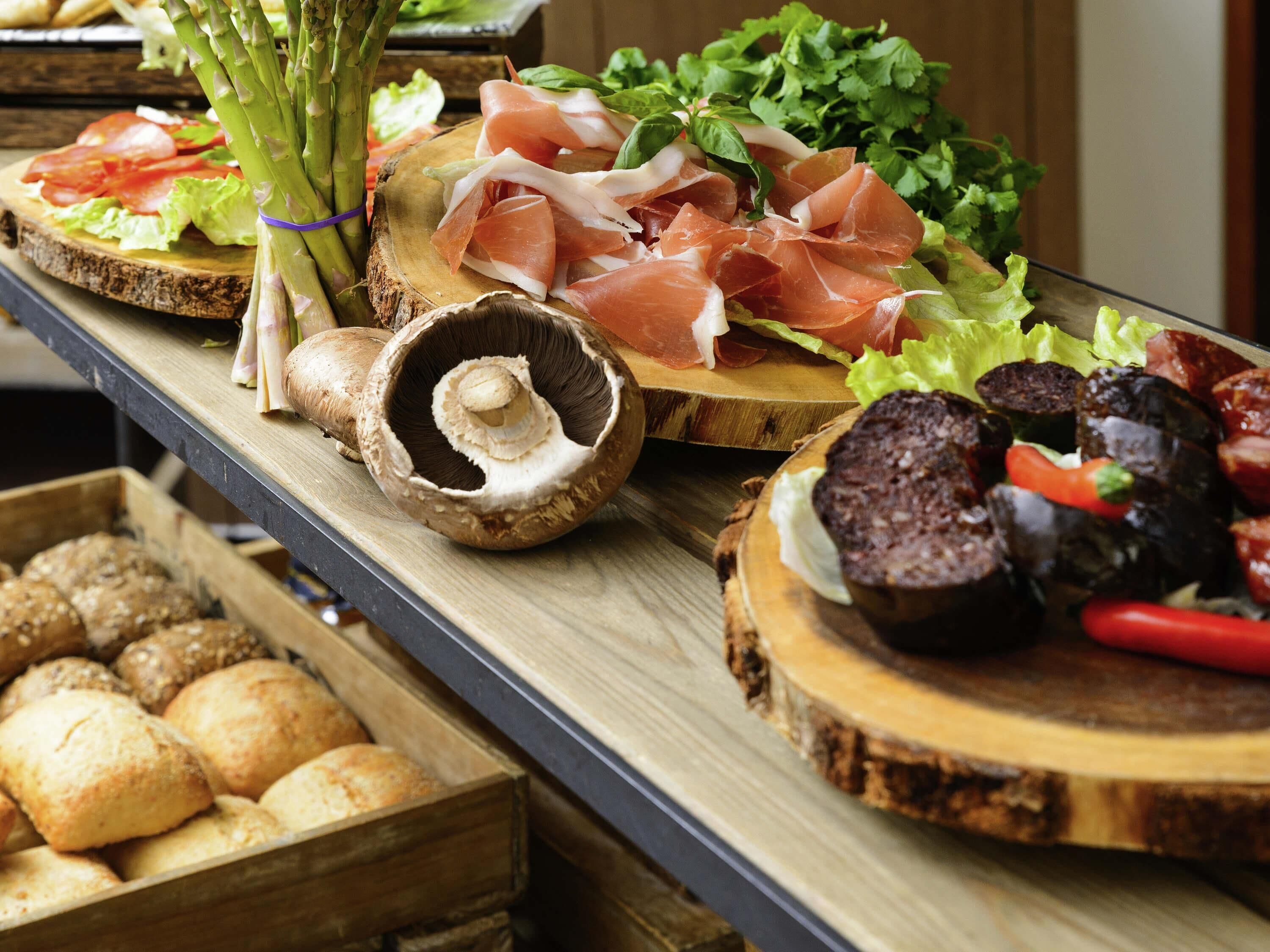 A buffet with various food items including bread, mushrooms, and vegetables.