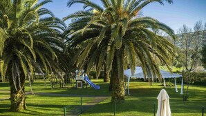 A park with palm trees, a playground, and a white tent. - Novotel Porto Gaia (Vila Nova de Gaia)