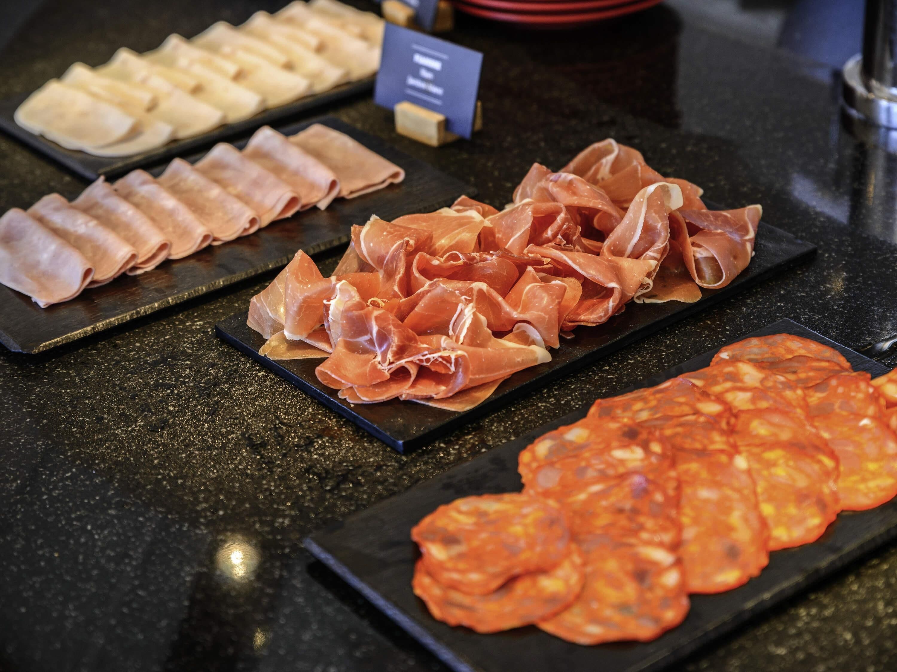A buffet with various types of cured meats and cheeses.