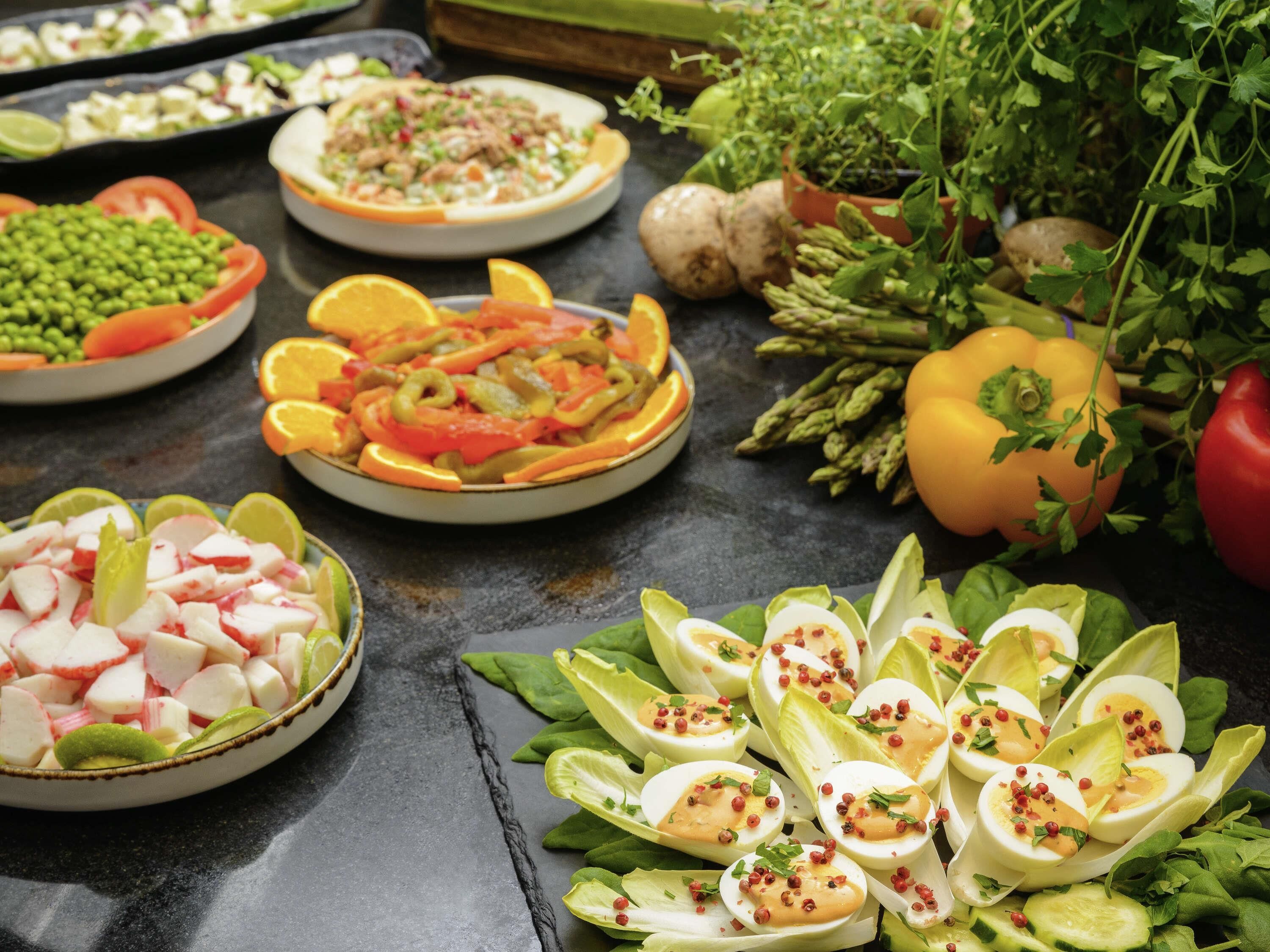 A variety of dishes including salads, vegetables, and egg cups.