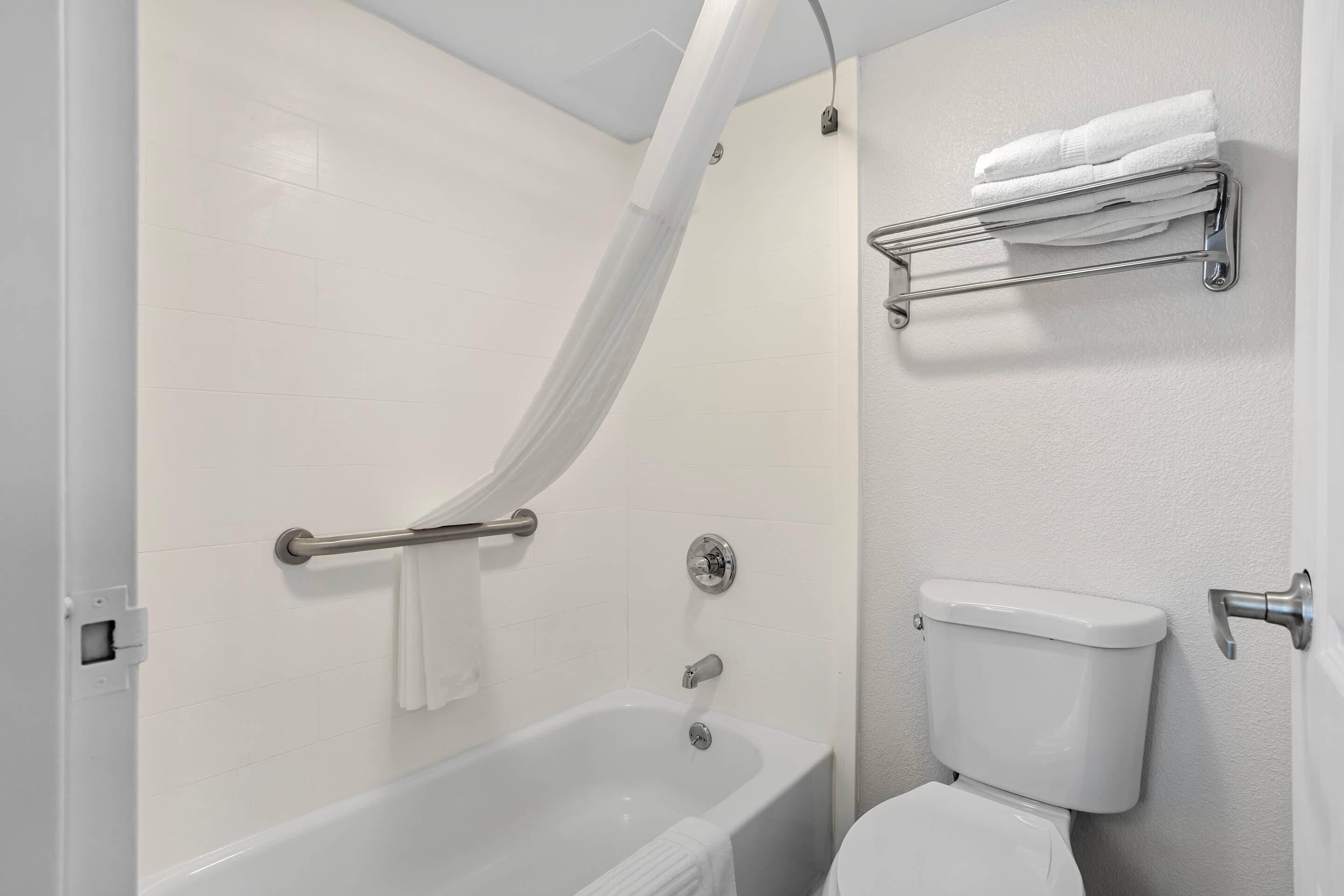 A bathroom with a bathtub, toilet, towel rack, and a shower curtain.