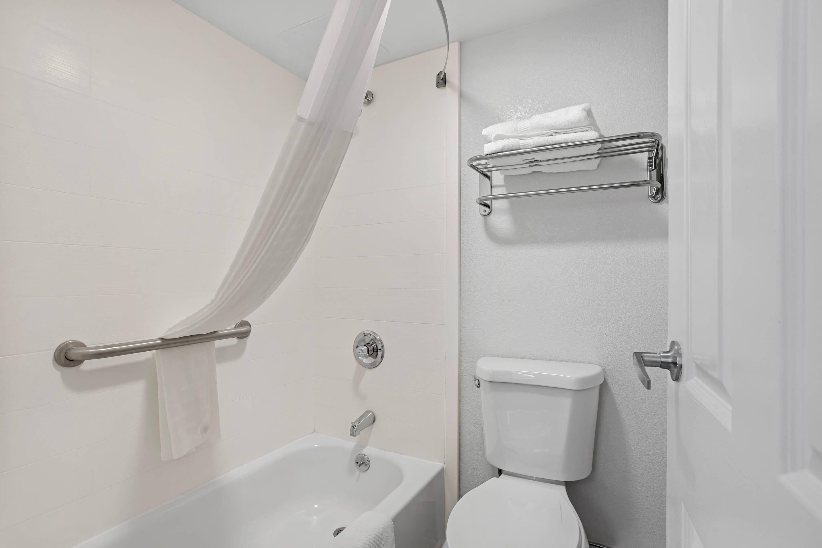 A bathroom with a bathtub, toilet, and a towel rack.