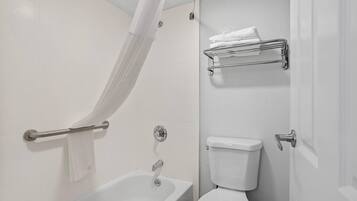 A bathroom with a bathtub, toilet, and a towel rack.