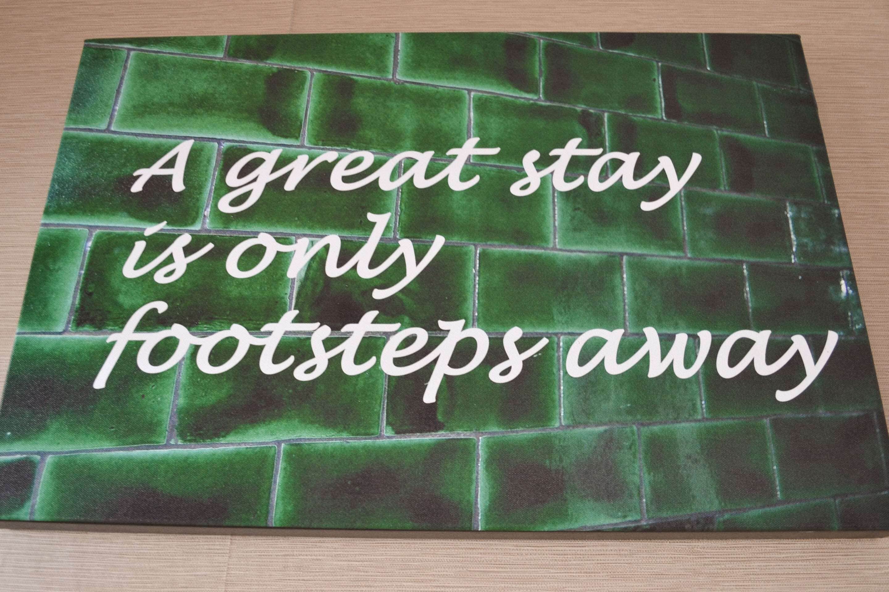 Pared verde con baldosas y el texto "Un gran alojamiento está a solo unos pasos".