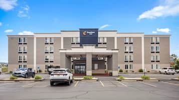 A Comfort Inn hotel with a modern facade, a parking lot, and a clear blue sky.