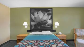 A hotel room with a bed, two bedside tables, a nightstand, a lamp, and a large framed picture on the wall.