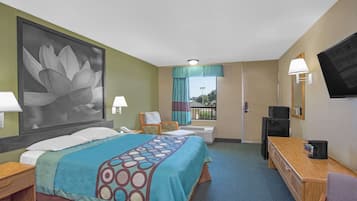 A hotel room with a bed, a desk, a TV, and a large window with a view of the outdoors.