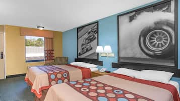 A hotel room with two beds, a window with a view, and a large tire poster on the wall.