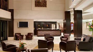A spacious lobby with leather armchairs, a reception desk, and a flat-screen TV mounted on the wall.