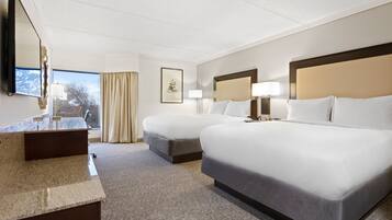 A hotel room with two beds, a desk, and a large mirror.