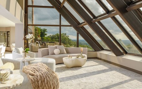 A modern interior with a high ceiling, large windows, and a view of the outdoors.