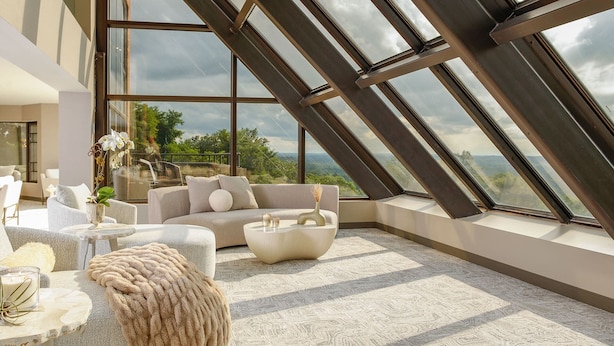 A modern interior with a high ceiling, large windows, and a view of the outdoors.