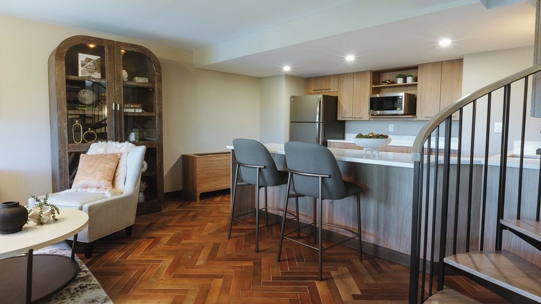 A modern kitchen with a herringbone floor pattern, a built-in microwave, and a stainless steel refrigerator.