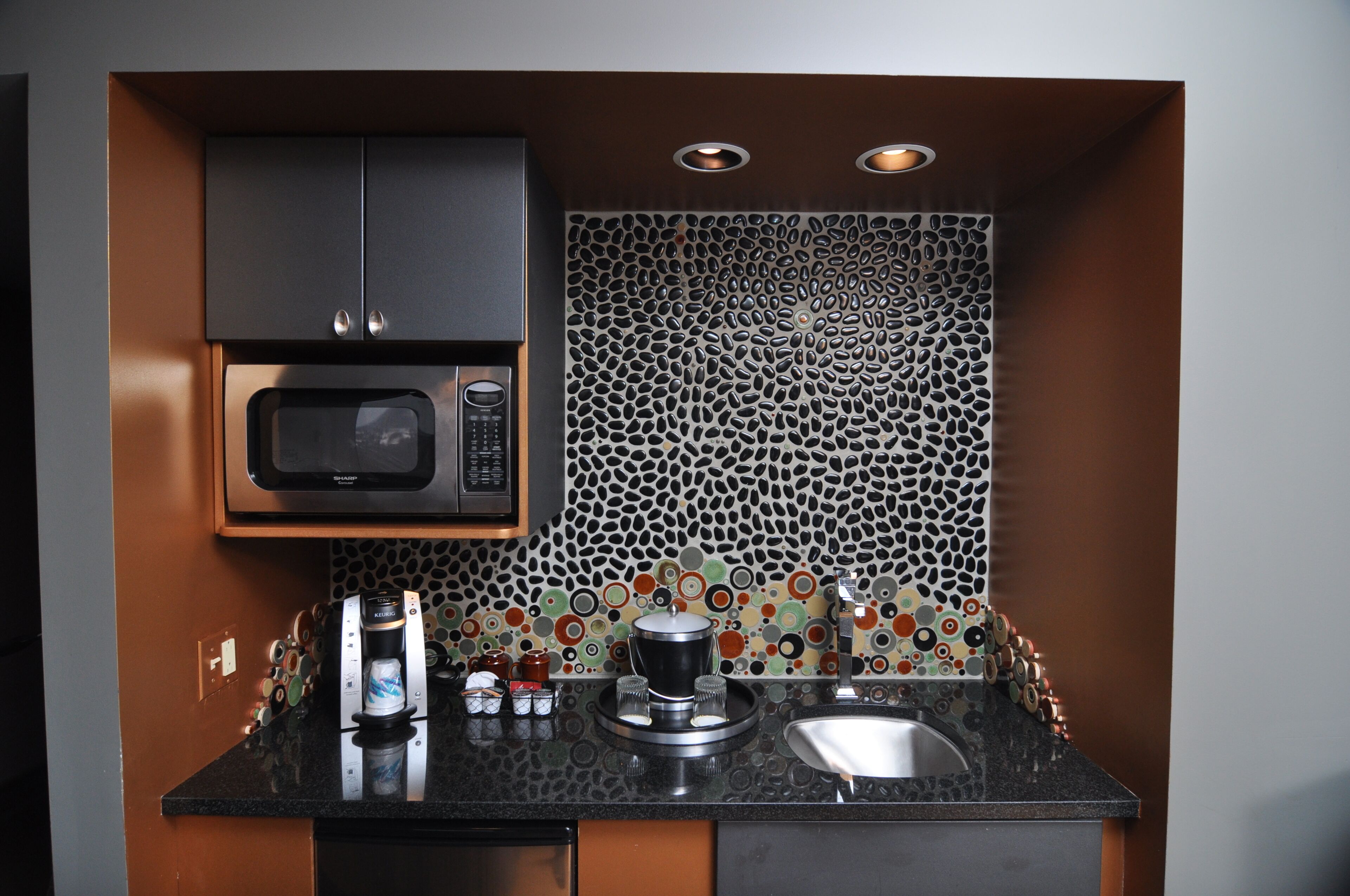 Cocina compacta con microondas, cafetera y lavabo.