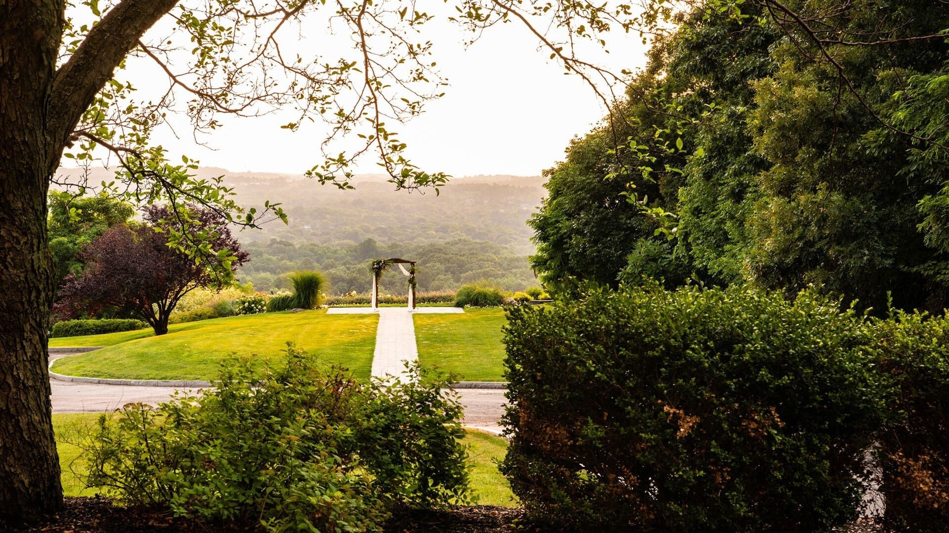 A pathway leading to a gazebo in a well-maintained garden with trees and shrubs.