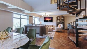 A spacious living area with a dining table, chairs, a sofa, a coffee table, and a staircase.