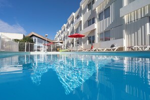 Relax by the rectangular pool surrounded by lounge chairs and umbrellas.