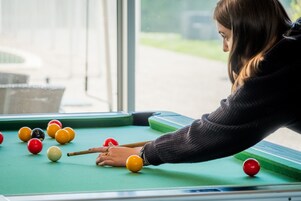 Una persona jugando billar en una mesa con superficie de fieltro verde.