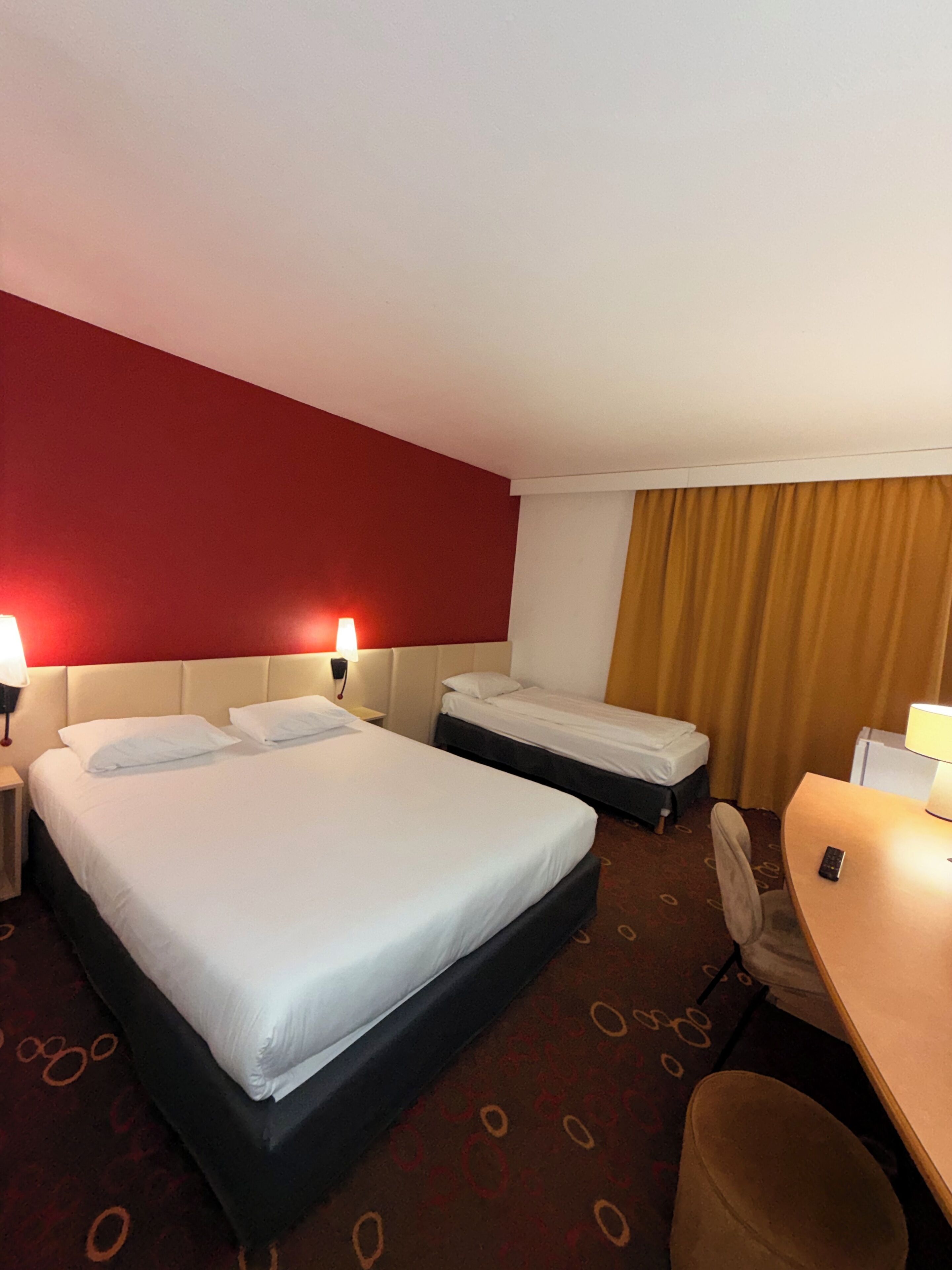 Une chambre d’hôtel avec deux lits, un bureau, une chaise et un téléphone.
