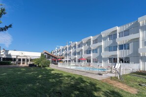 Un hotel moderno con piscina, zona de estar al aire libre y césped bien cuidado.