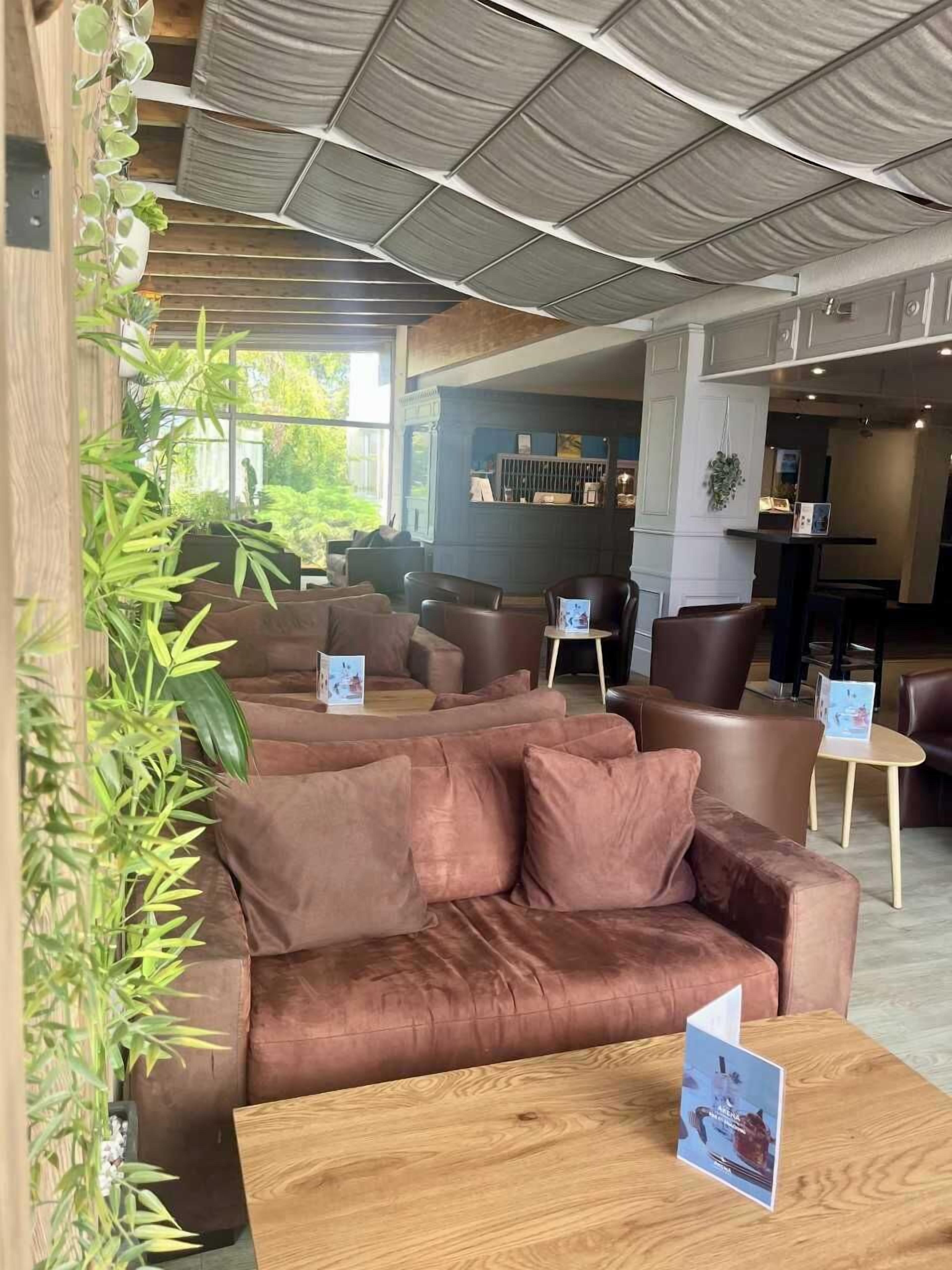 A modern interior with leather sofas, wooden tables, and a large plant.