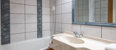 Un baño con bañera, lavamanos y espejo.