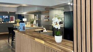 Un mostrador de recepción moderno con detalles de madera, una orquídea en maceta y un televisor montado en la pared.